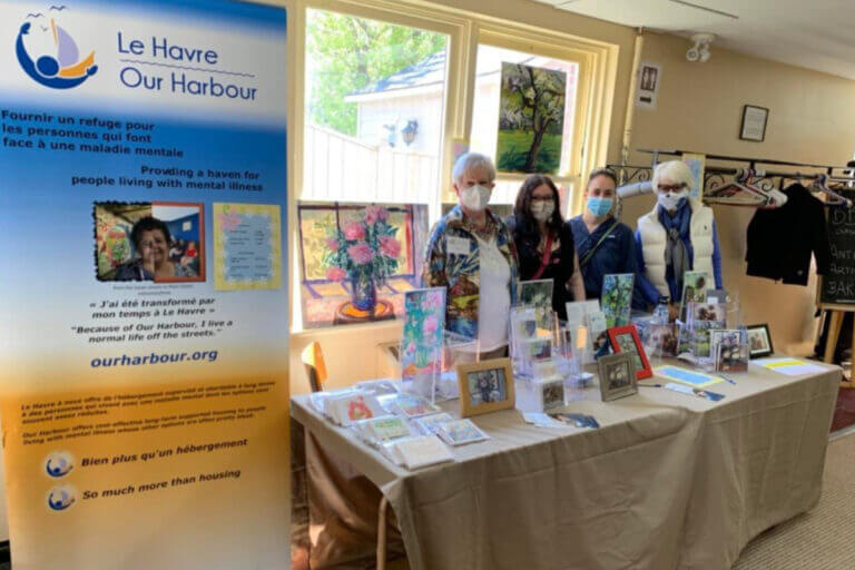 Image of Our Harbour staff next to a banner with a former Our Harbour Logo from our 2022 spring newsletter